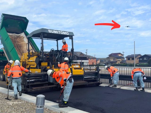 上空からドローンで撮影する。普段はなかなか目にすることのない舗装作業の様子。